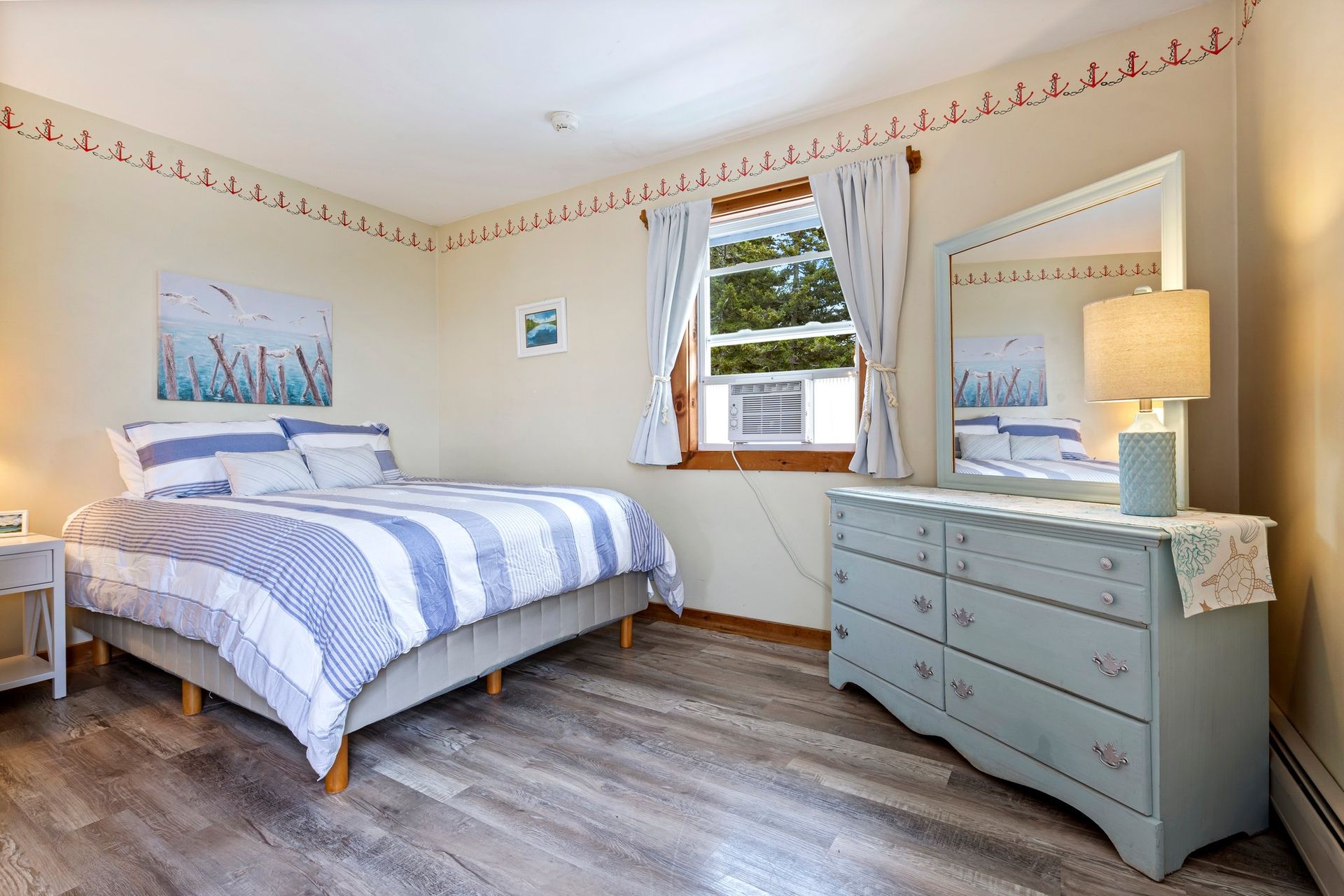 A bedroom with a bed , dresser , mirror and lamp.