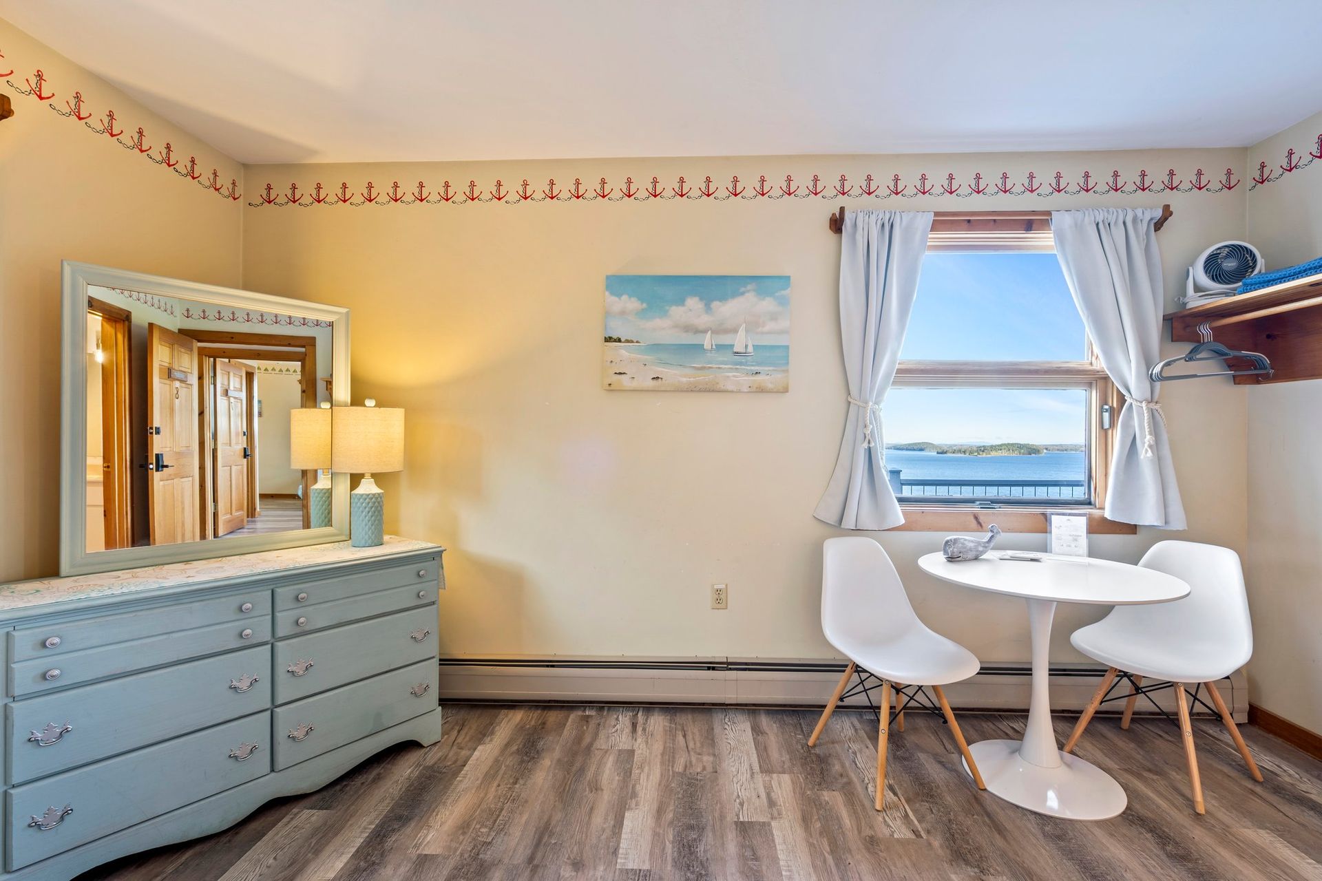Bedroom with a blue and white striped bed, a small nightstand, and a doorway to a bathroom. The walls are light yellow.
