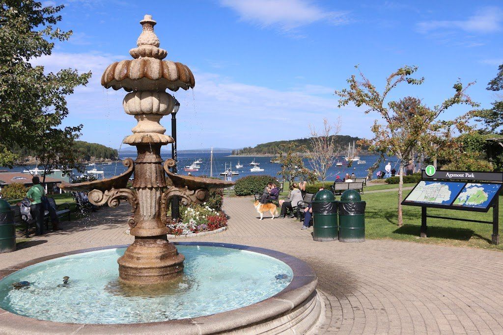 A fountain in a park with boats in the background