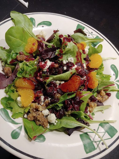A salad with oranges and cranberries on a plate