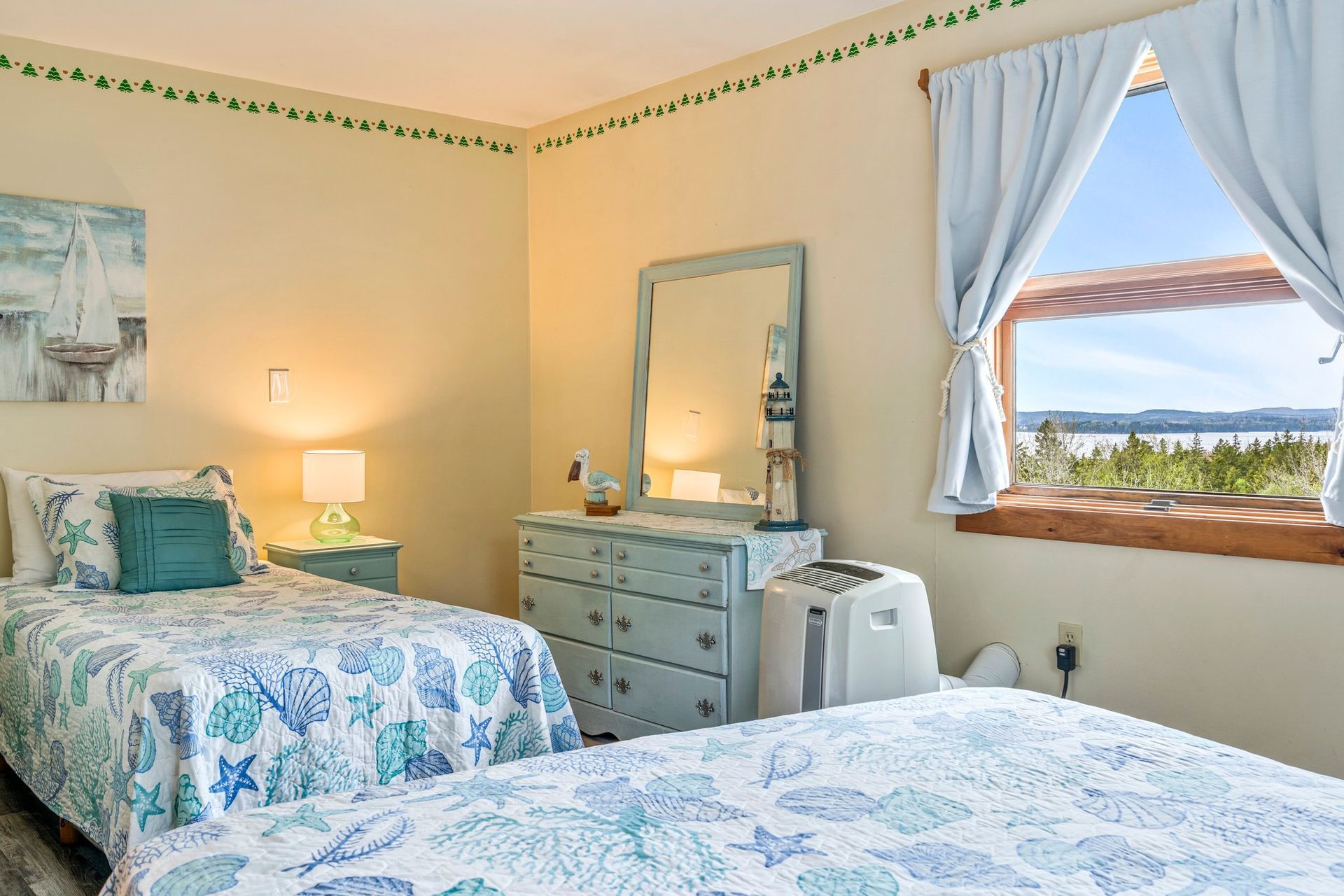 Inn room with a nautical theme. Features a bed, windows with curtains, and decorative wall art.
