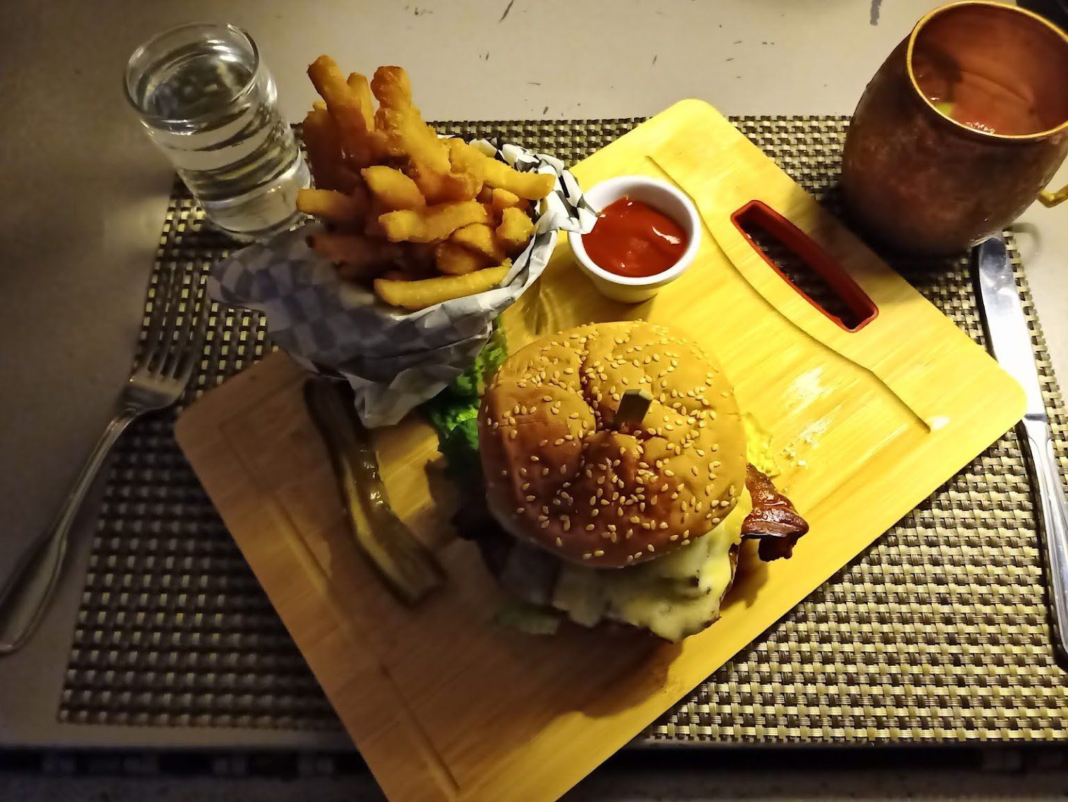A hamburger and french fries on a wooden cutting board