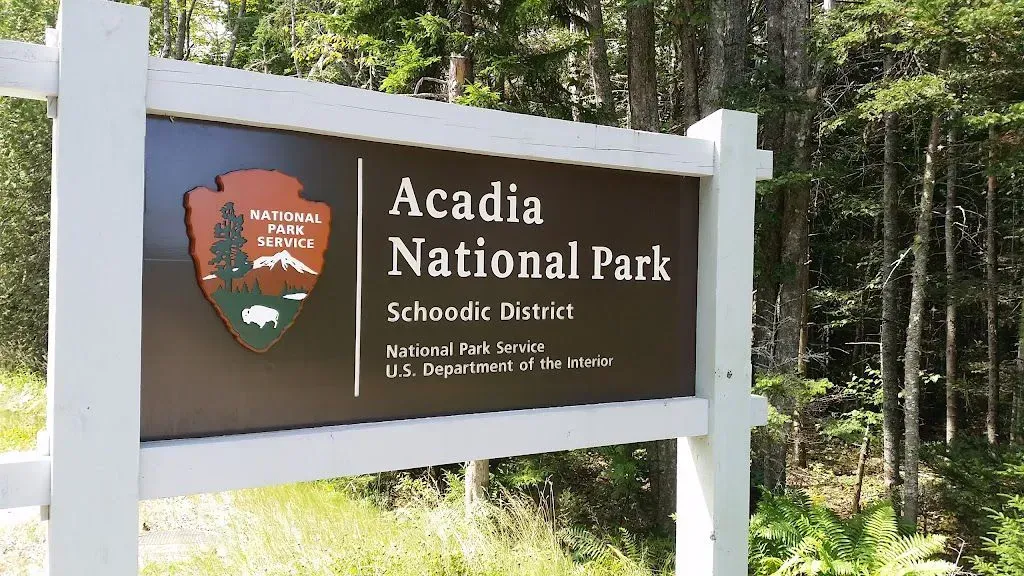A sign for acadia national park is surrounded by trees