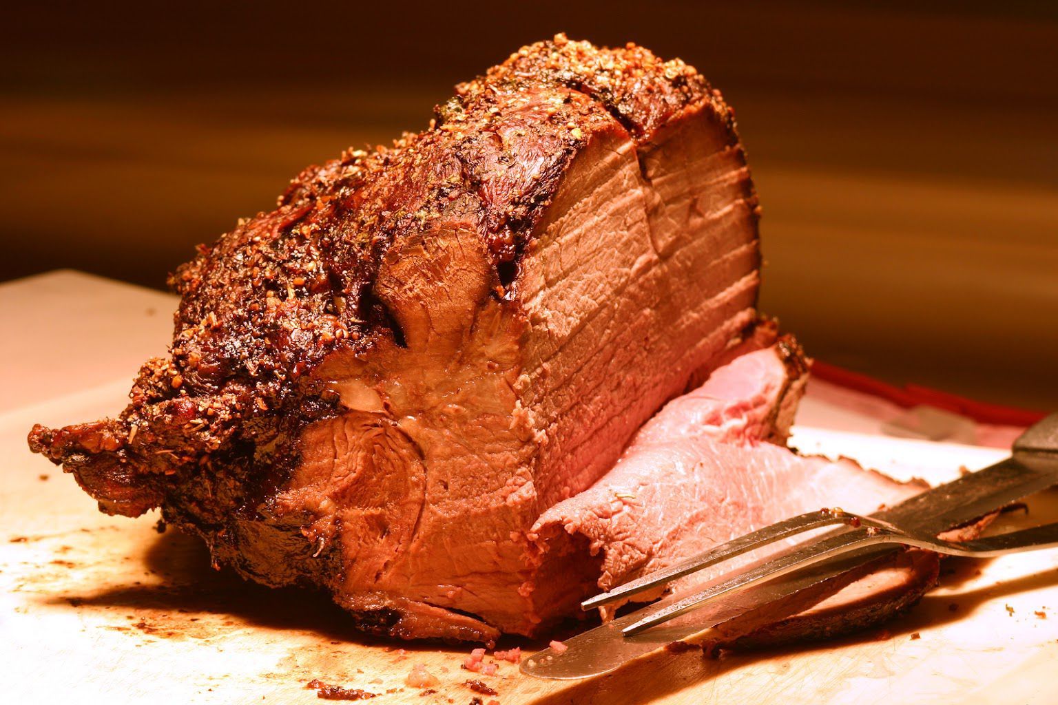 A piece of roast beef is sitting on a cutting board with a fork.