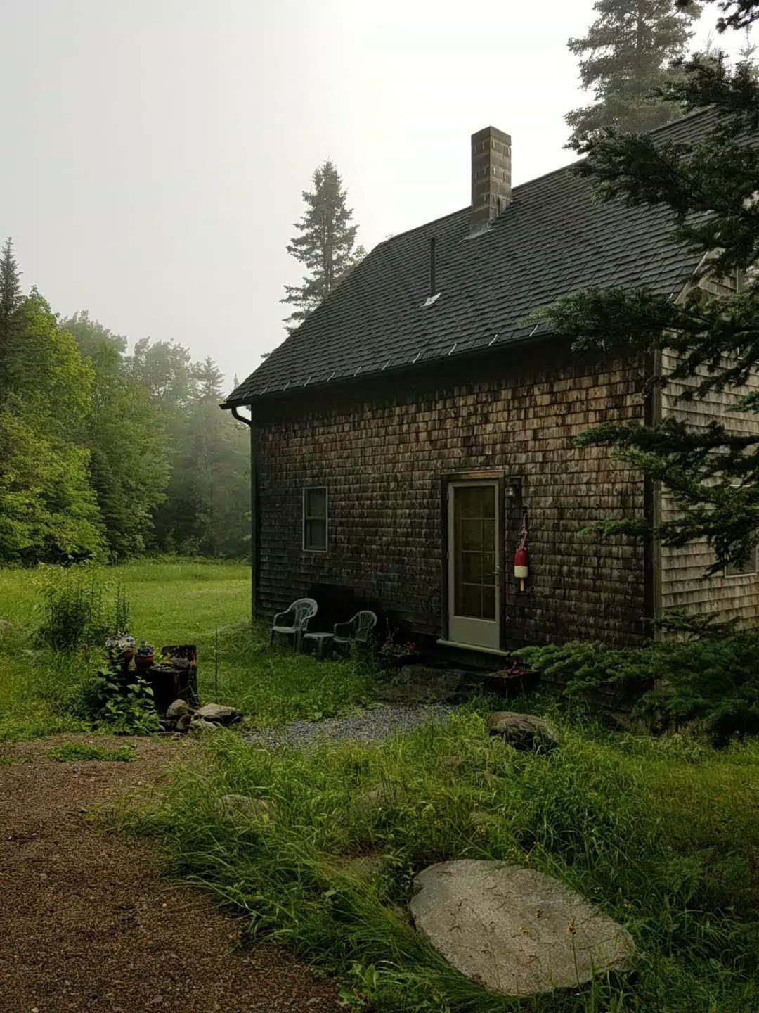 A brick house is sitting in the middle of a grassy field.