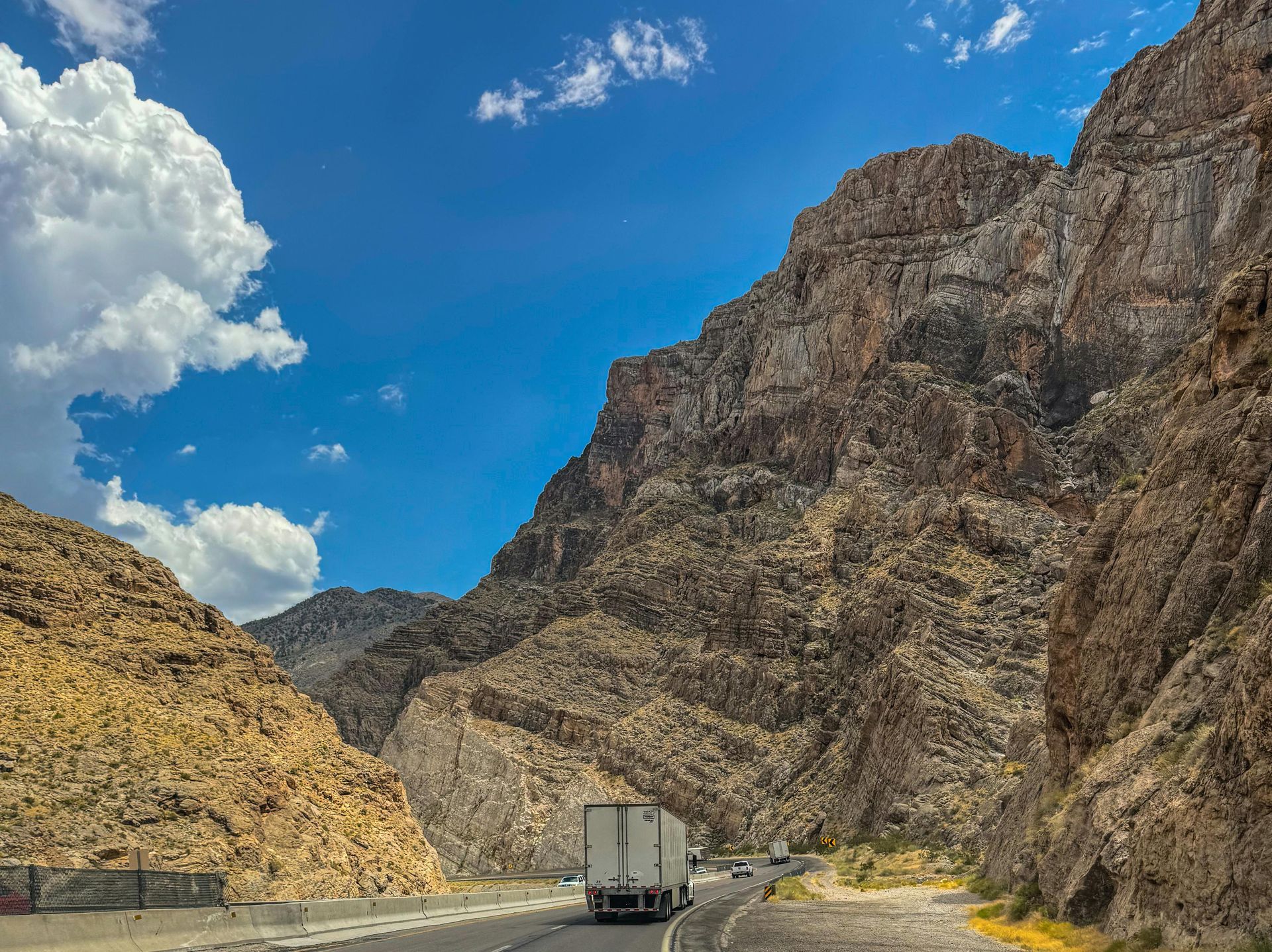 A truck is driving down a highway in the mountains.