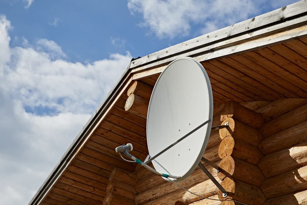A Satellite Dish Is Hanging From The Roof Of A Log Cabin — Coastwide Antennas In Avoca, NSW
