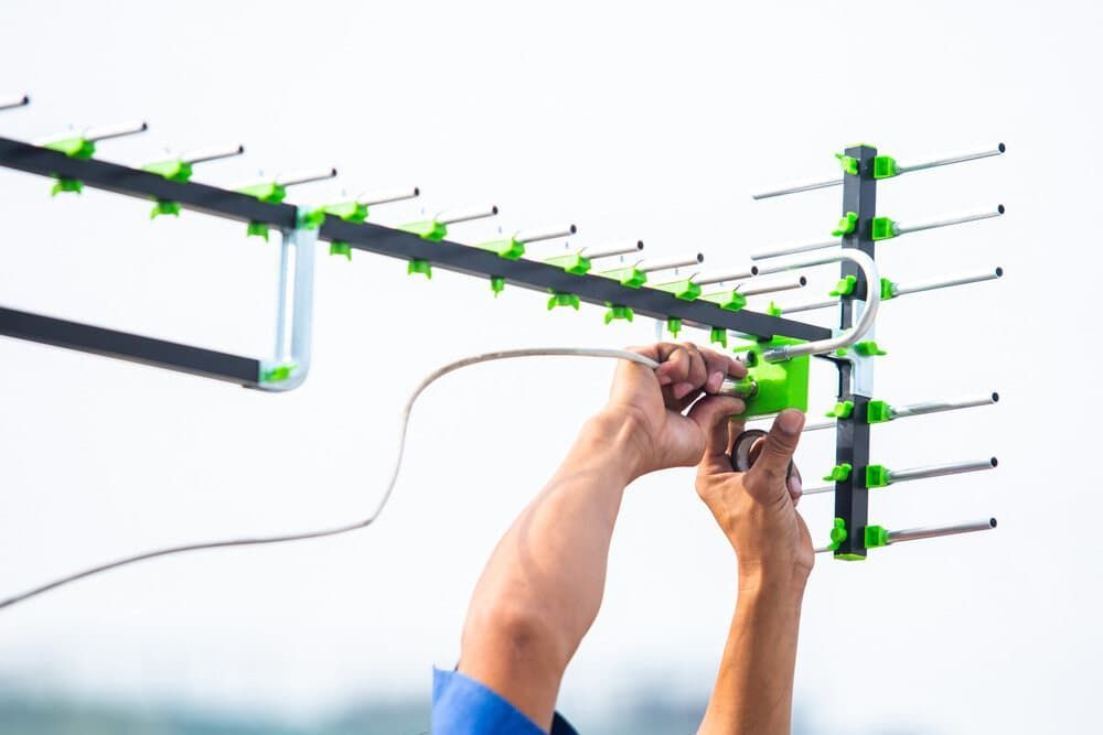 A Man Is Installing An Antenna On A Roof — Coastwide Antennas In Gosford, NSW