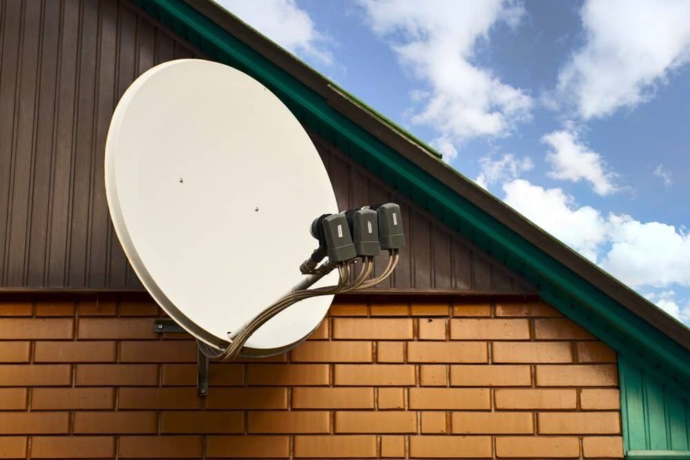 A Satellite Dish Is Mounted On The Side Of A Brick Building — Coastwide Antennas In Ourimbah, NSW