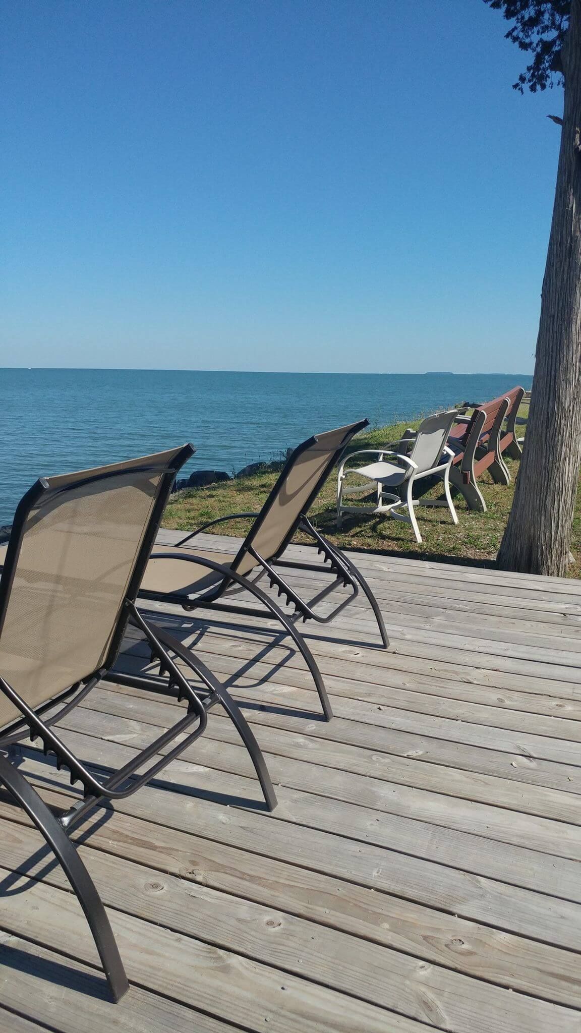 A wooden deck with chairs and a table overlooking Lake Erie at Scenic Rock Ledge Inn