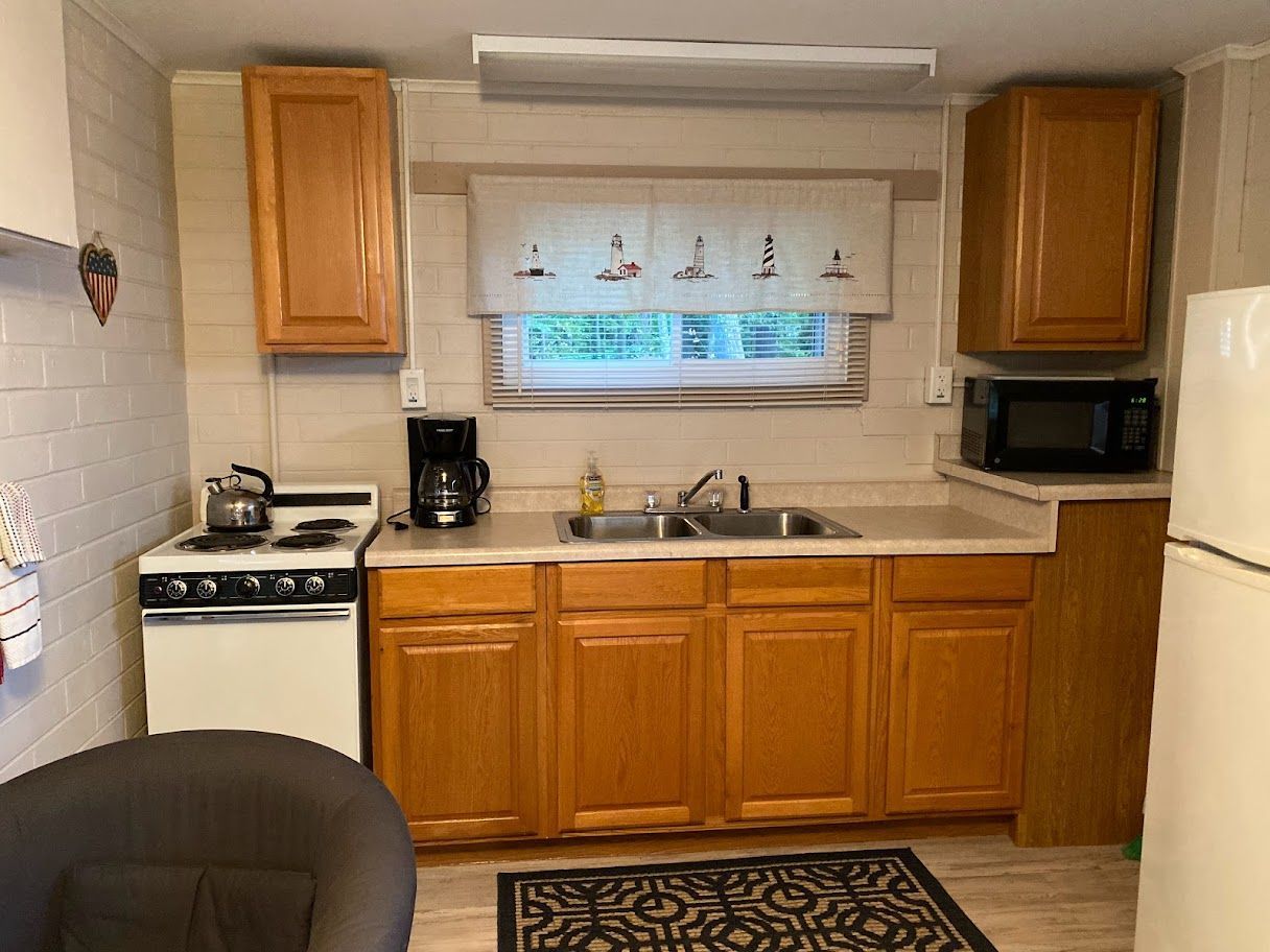 A kitchen with a stove , sink , refrigerator and microwave.