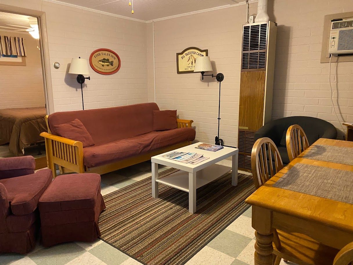 A living room with a couch , chairs , a table and a mirror.