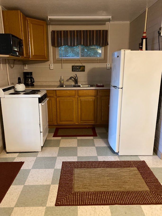 A kitchen with a stove , refrigerator , sink and microwave.