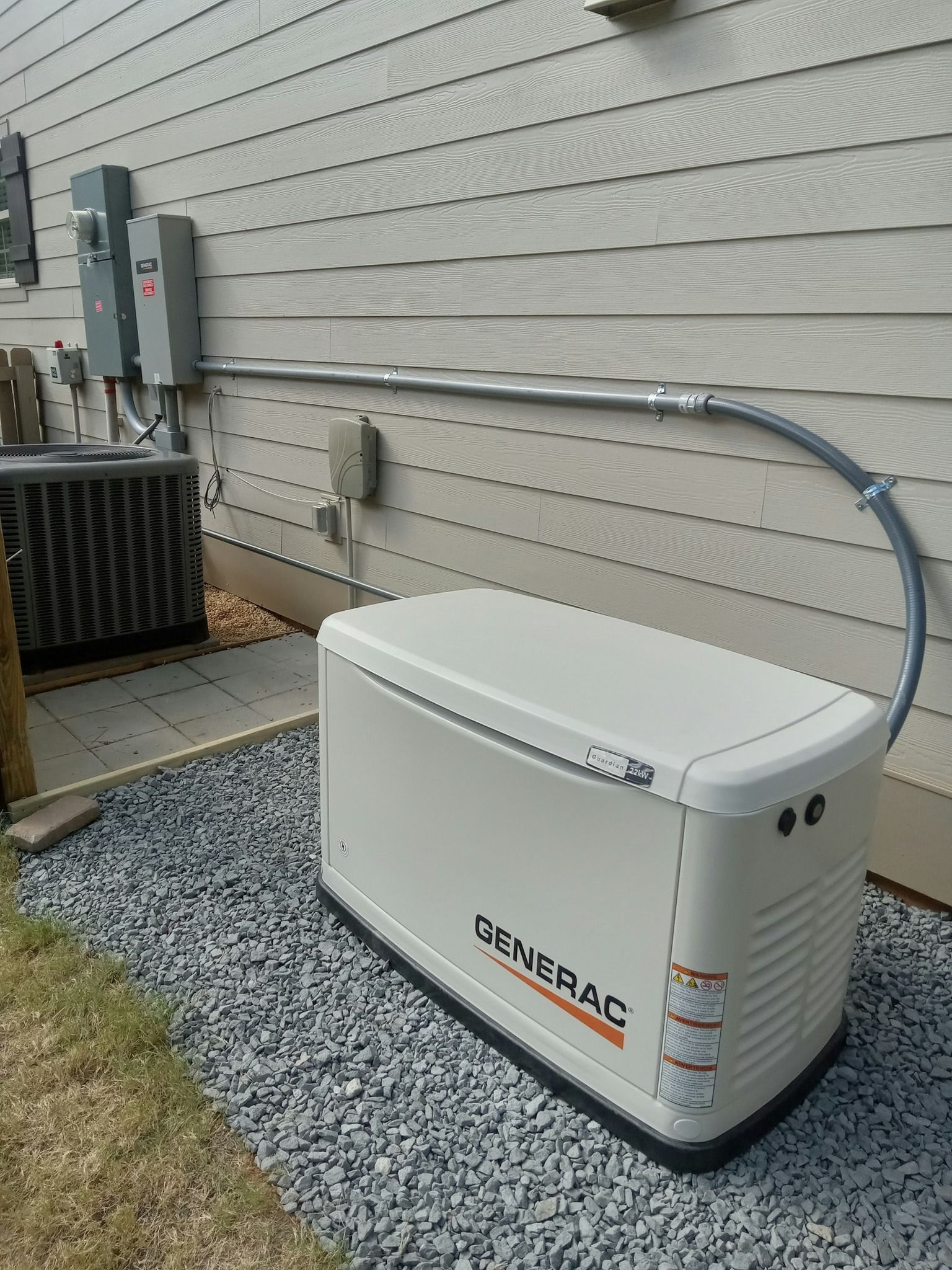 A generator is attached to the side of a house.