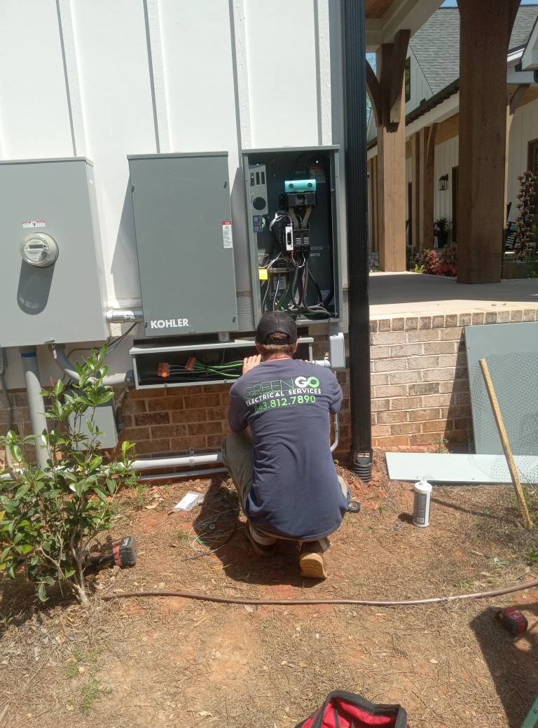 A man is kneeling down in front of a box on the side of a building.