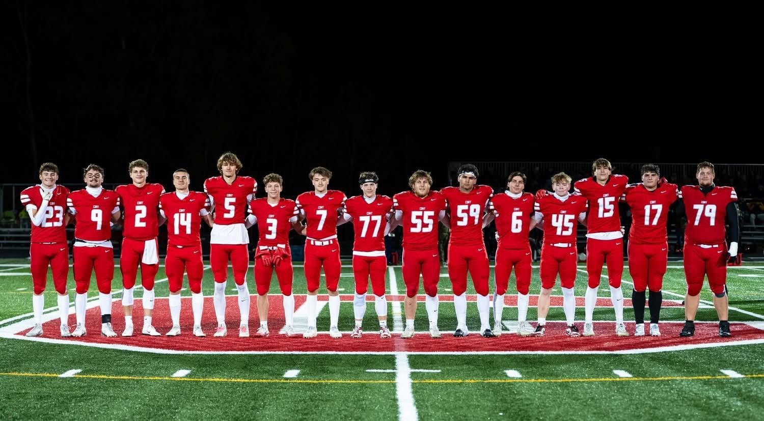Football team in red uniforms standing on a field at night.