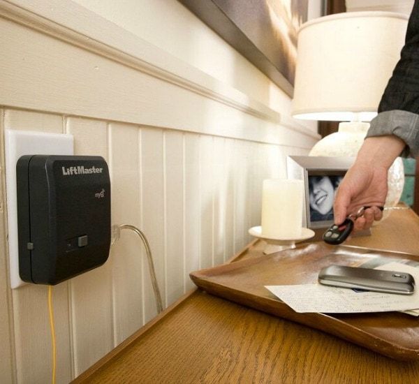 a person is holding a remote next to a lift master device