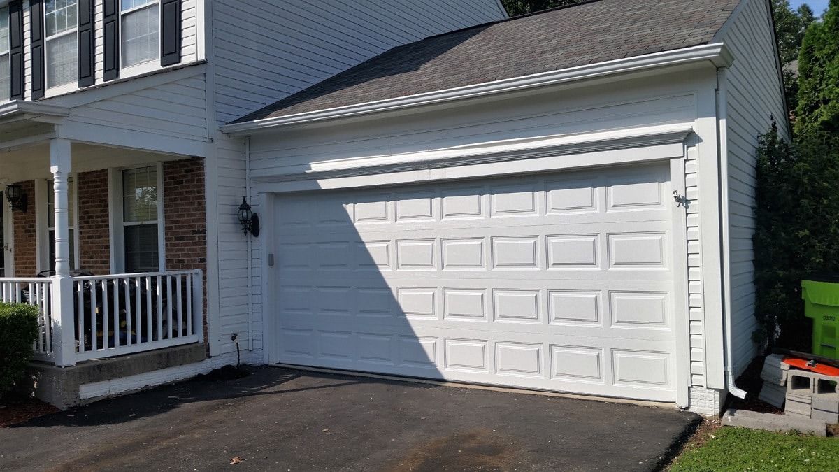 A white garage door is sitting in front of a brick house.
