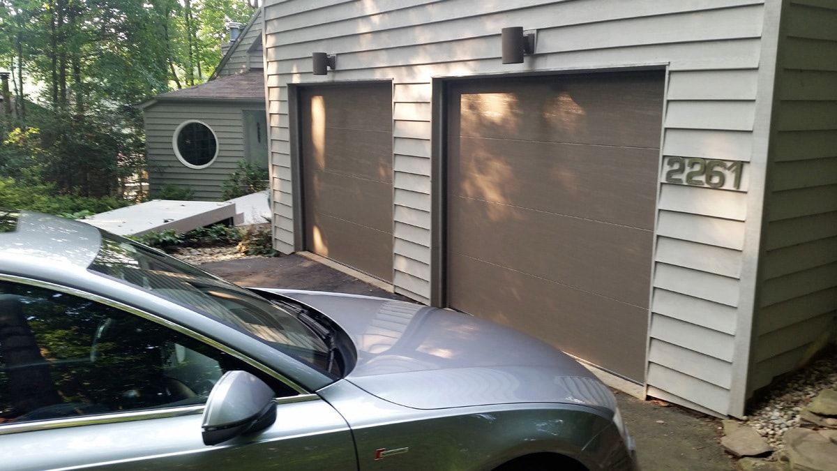 A car is parked in front of a garage with the number 2351 on it