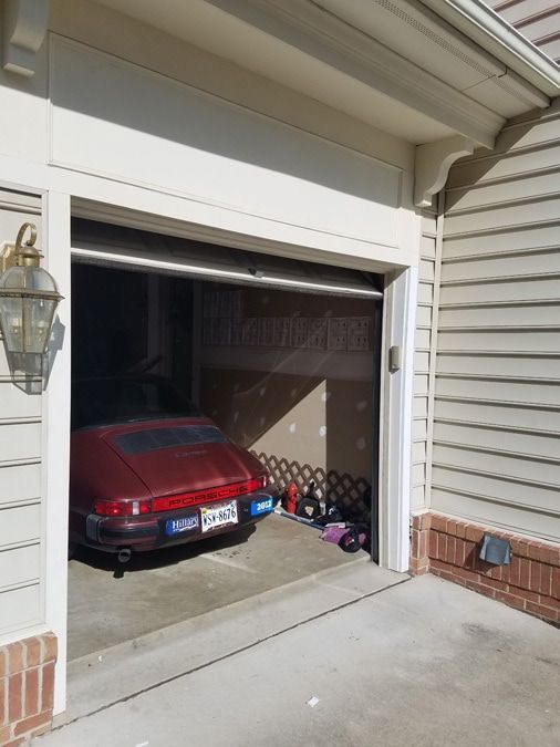 A red car is parked in a garage with the door open