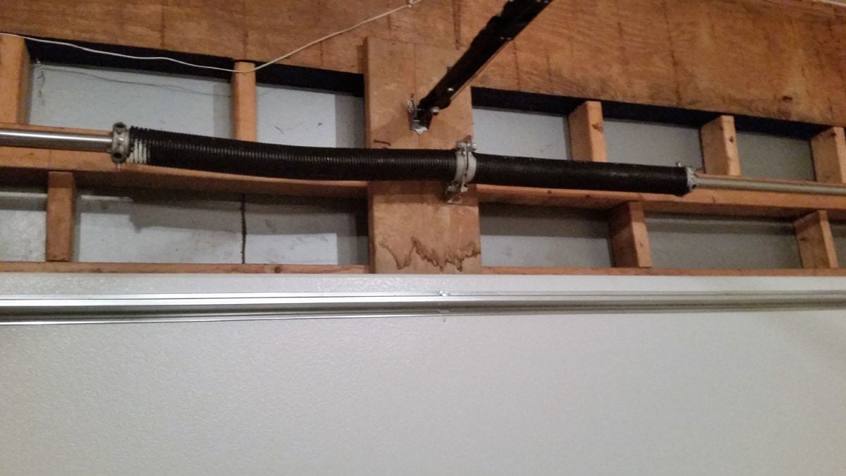A garage door spring is hanging from the ceiling of a garage.