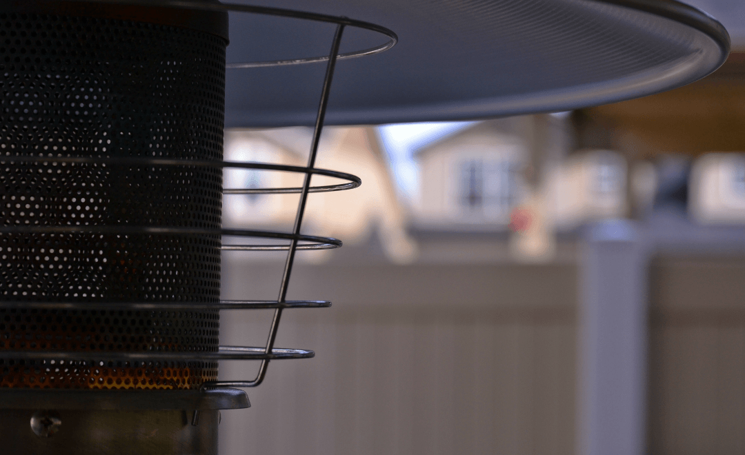 A close up of a patio heater with a house in the background