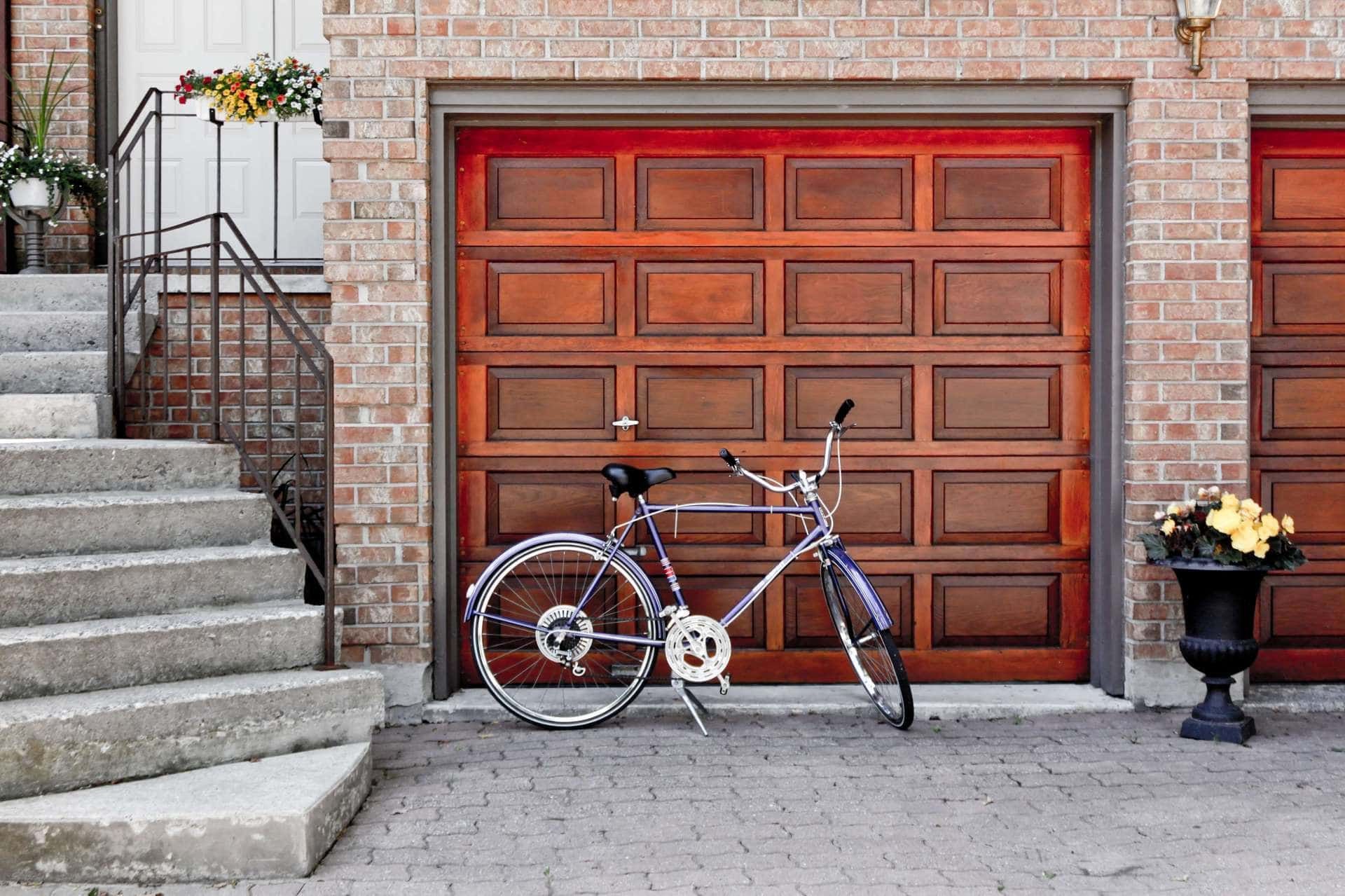 A bicycle is parked in front of a wooden garage door.