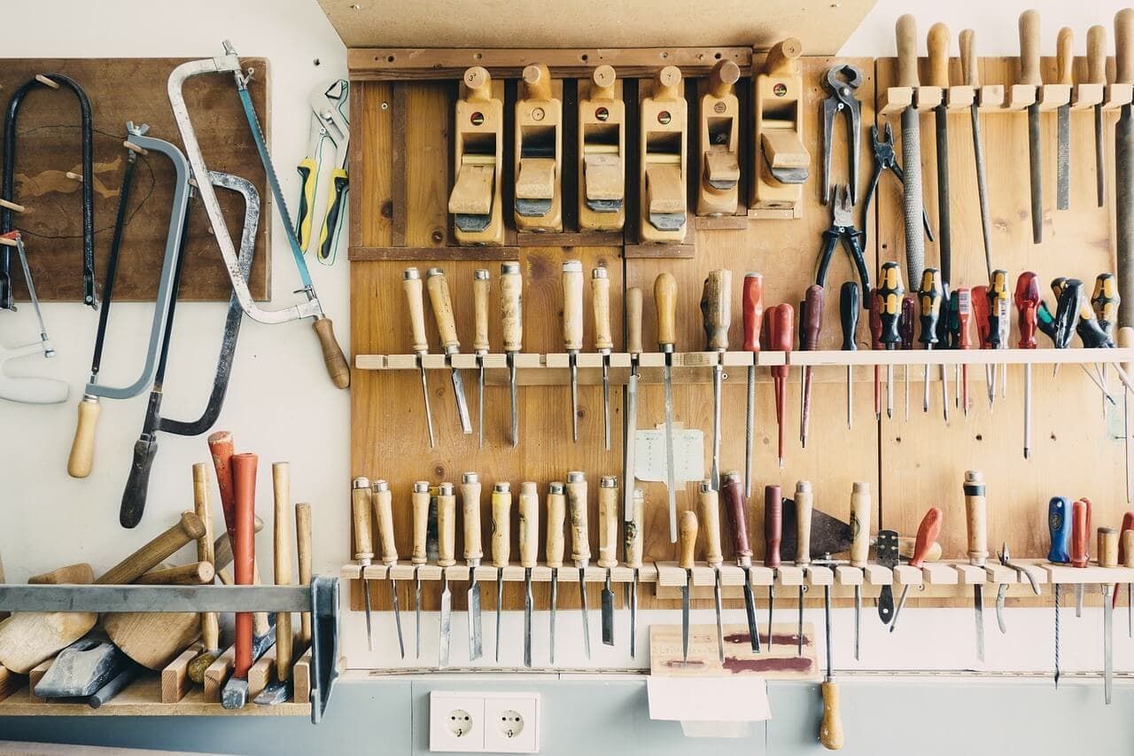 A wooden wall with a bunch of tools hanging on it.