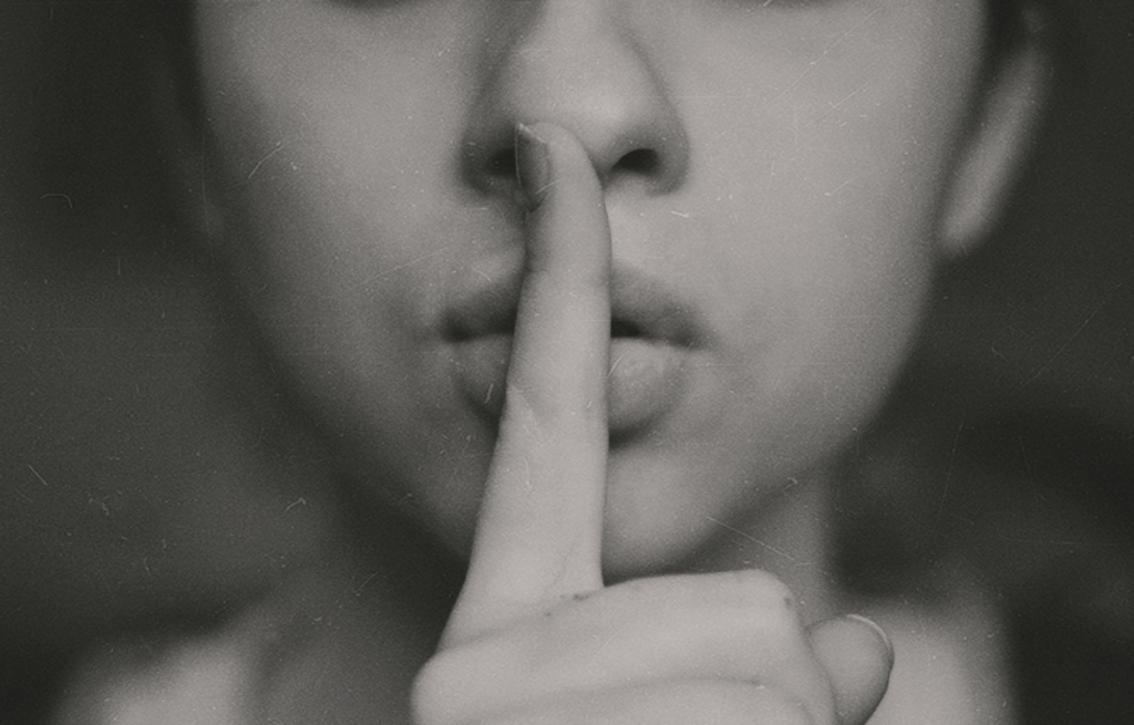 A woman is holding her finger to her mouth in a black and white photo.