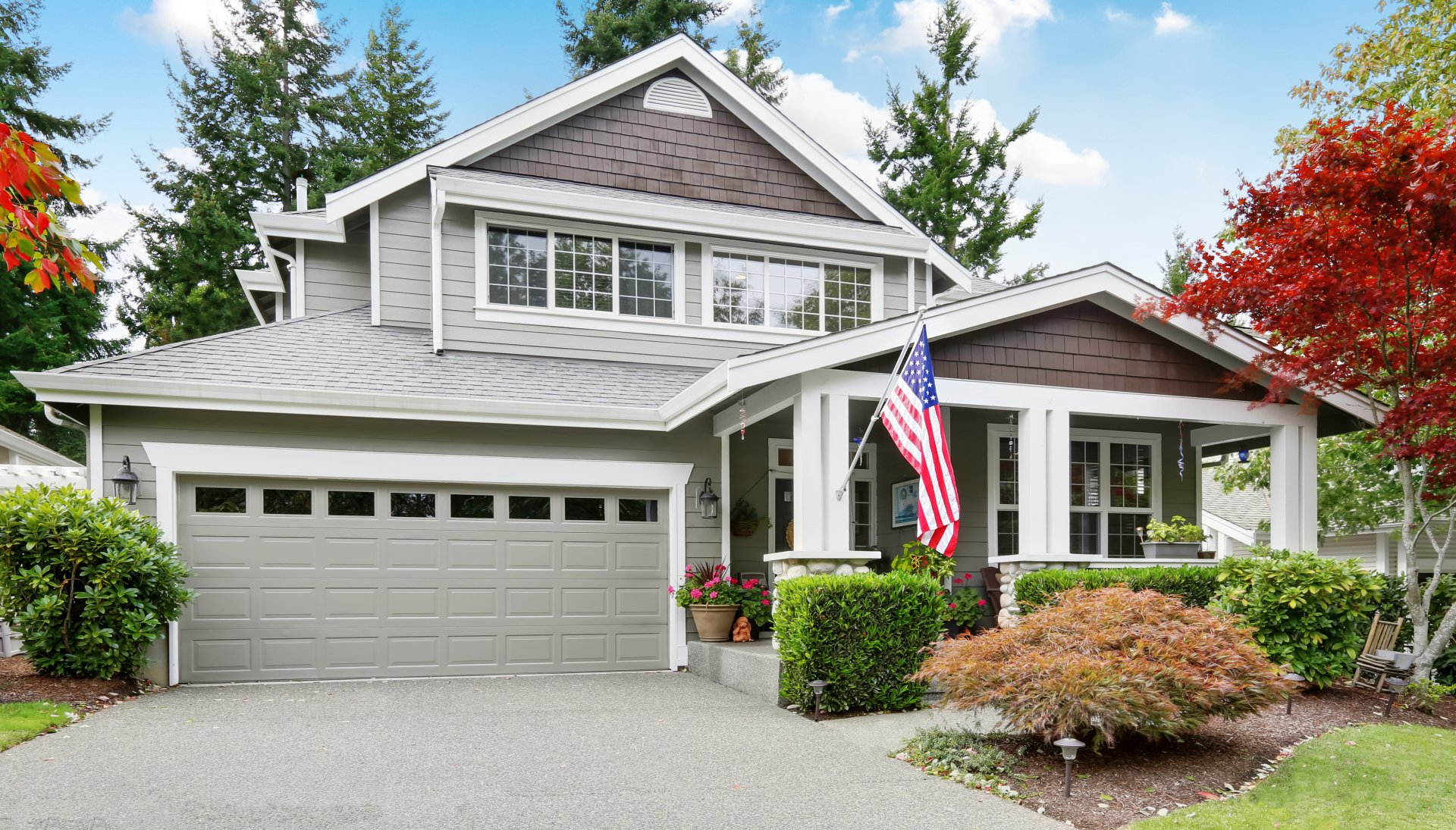 A large house with a garage and an american flag in front of it.