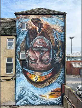 A large mural on the side of a building of a man with a beard.