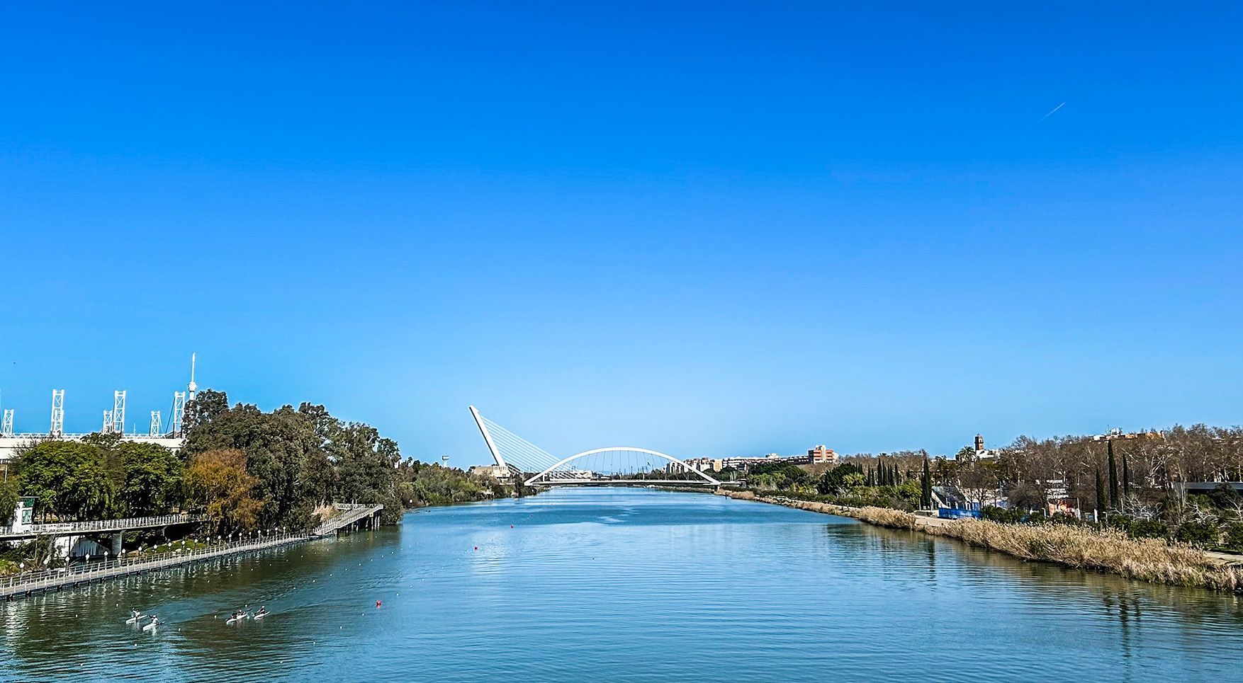A river with a bridge in the background on a sunny day in Seville