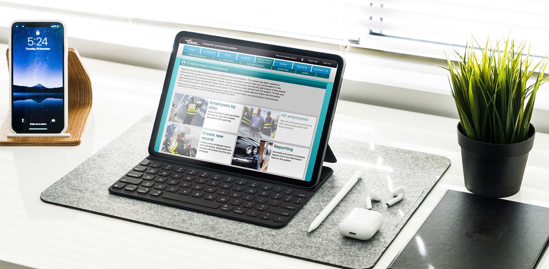 A laptop is sitting on top of a desk next to a potted plant and a cell phone with 