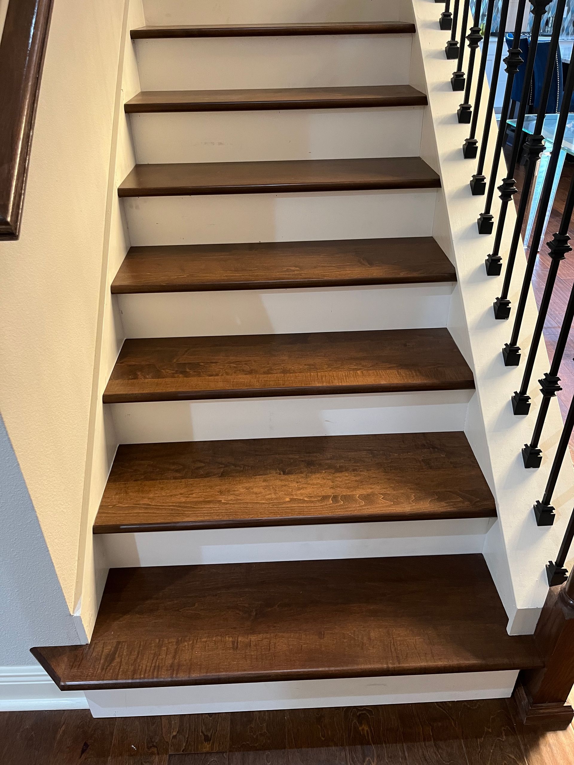 Wooden staircase with dark brown steps and white risers, leading upwards.