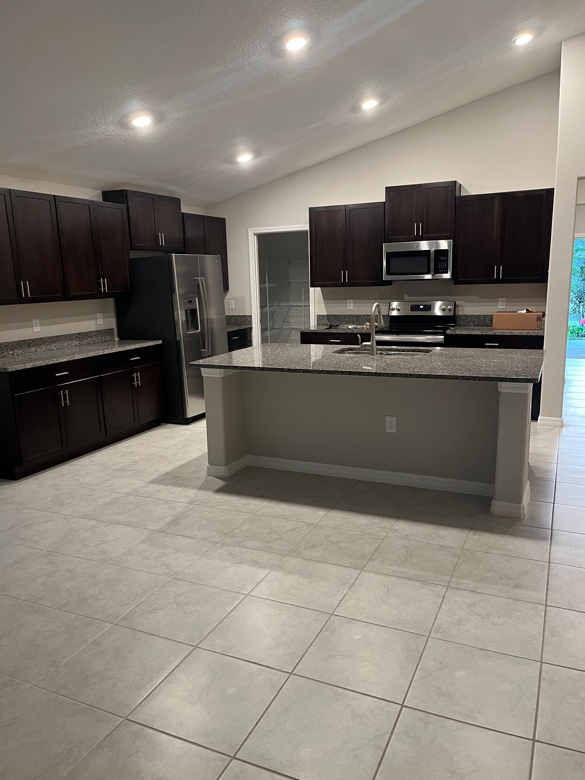 Modern kitchen with dark cabinets, stainless steel appliances, and a gray island.