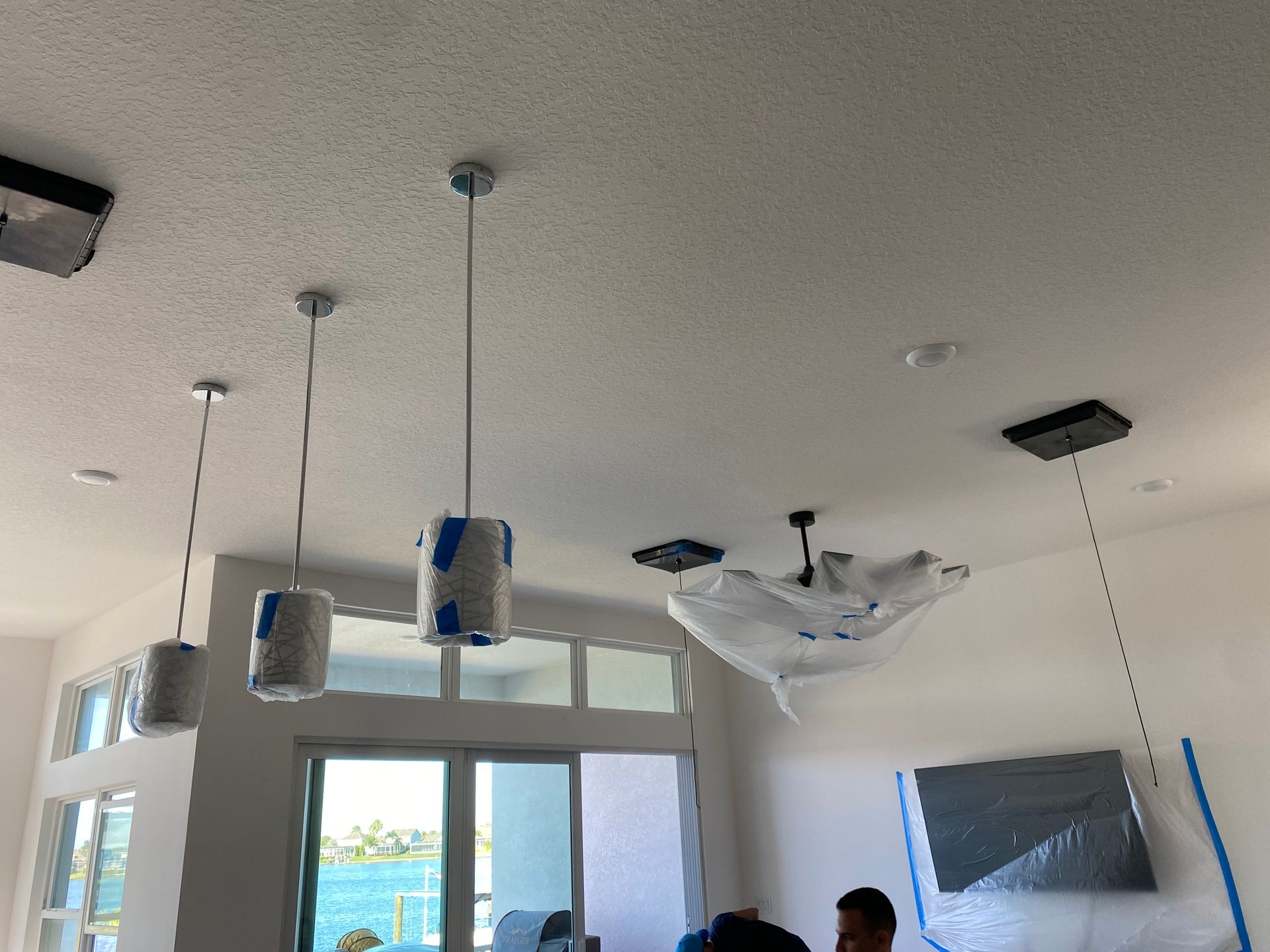 White ceiling with pendant lights and a covered chandelier.
