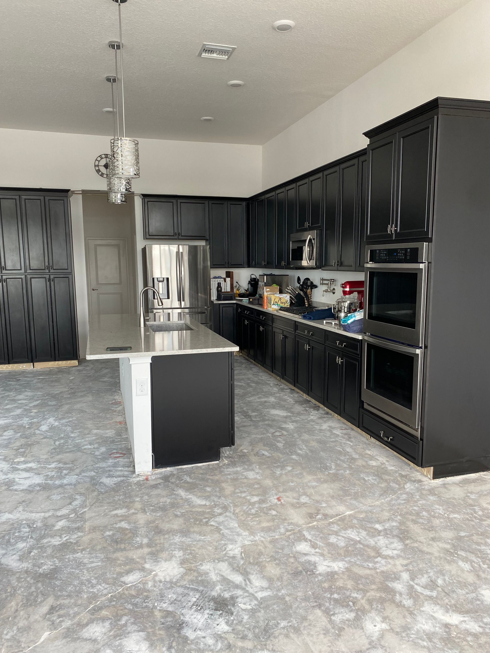 Black kitchen cabinets with stainless steel appliances; island in foreground.