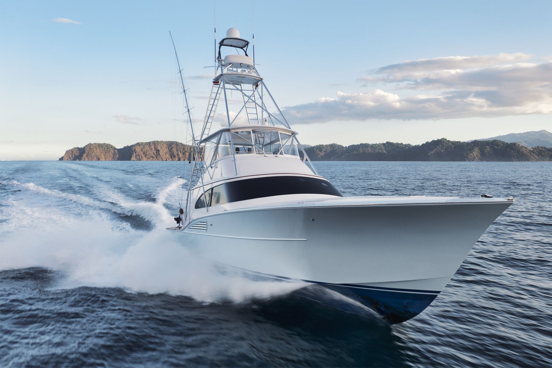 A white fishing boat speeds across blue ocean water