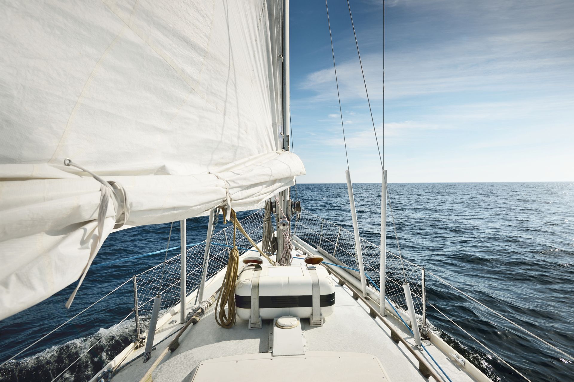 Sailboat sailing on a bright blue ocean under a sunny sky