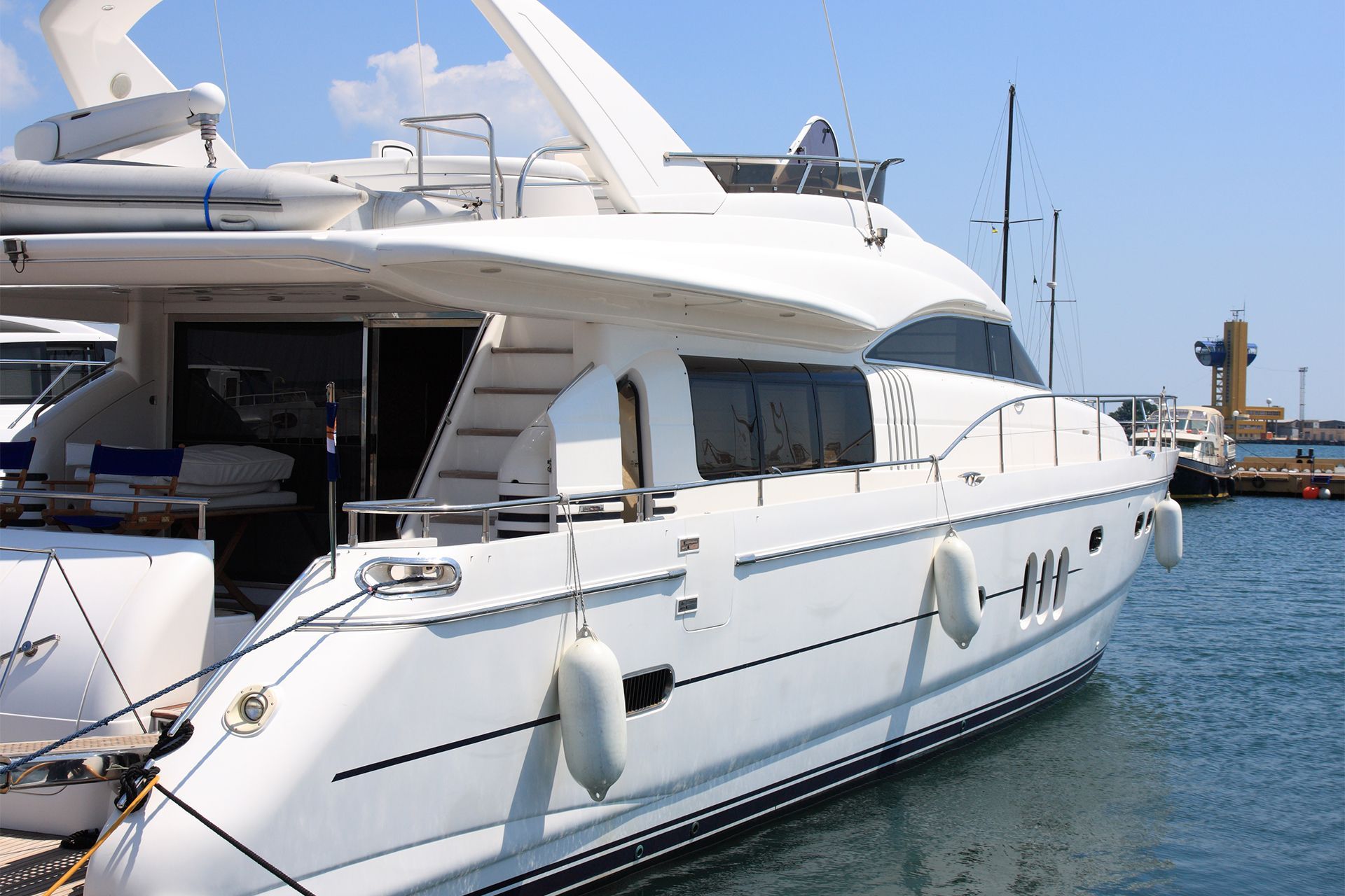 White yacht docked at a marina on a sunny day