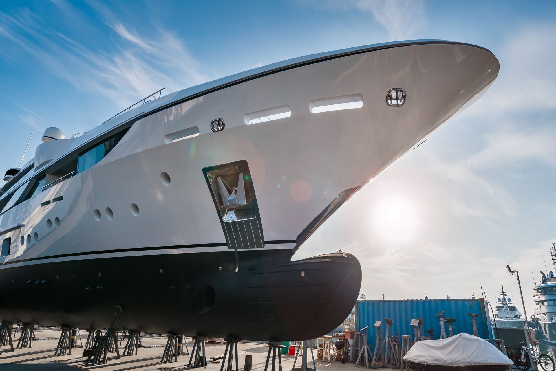 Large, white yacht in dry dock under a bright blue sky