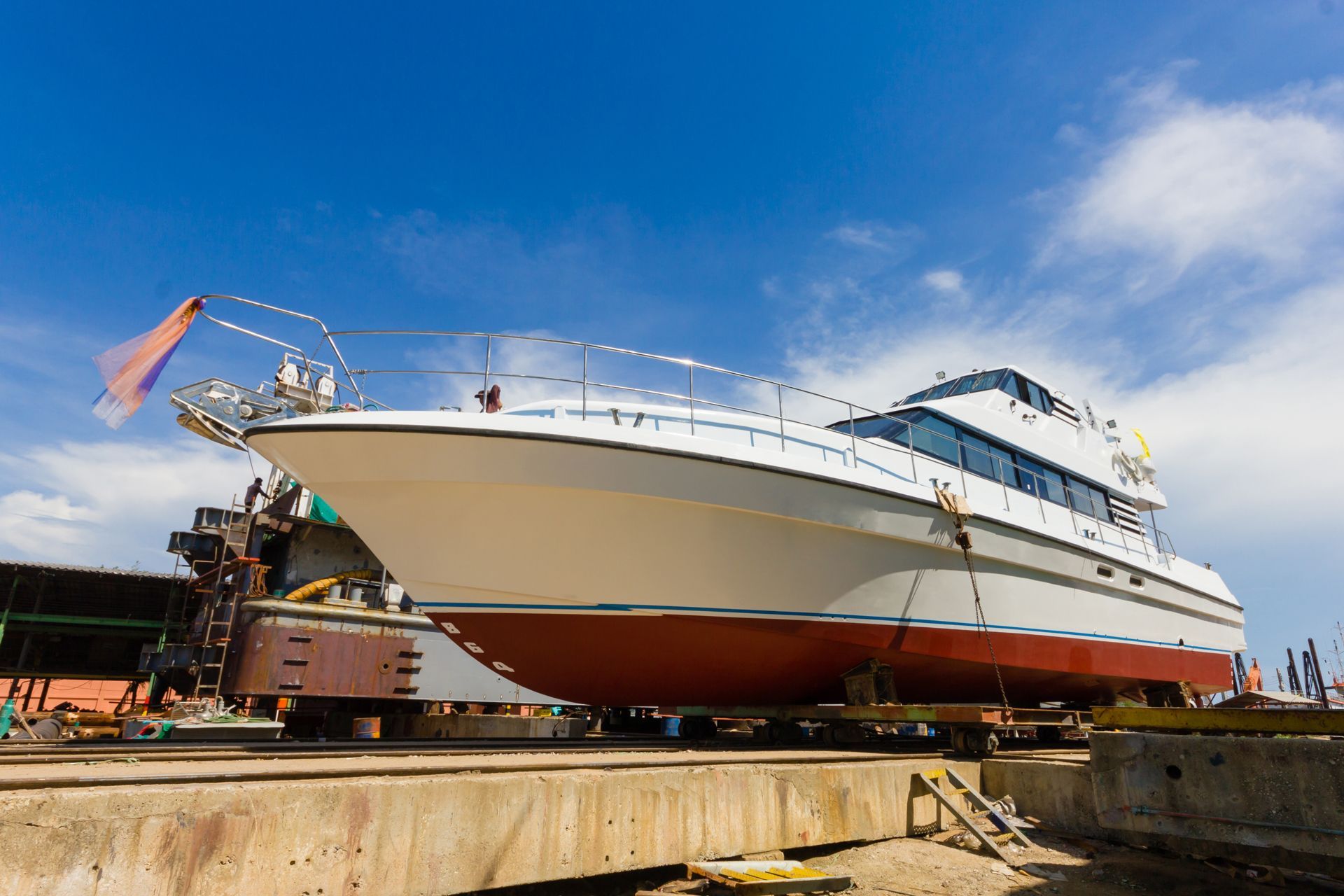 A white and red boat on a dry dock under a blue sky