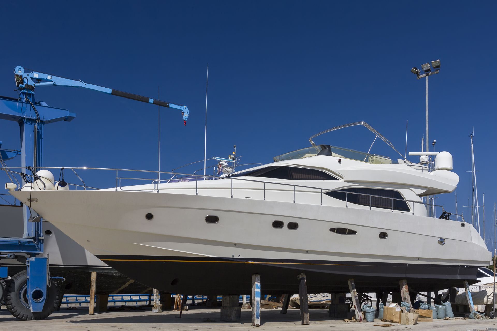 A large white yacht on supports at a shipyard