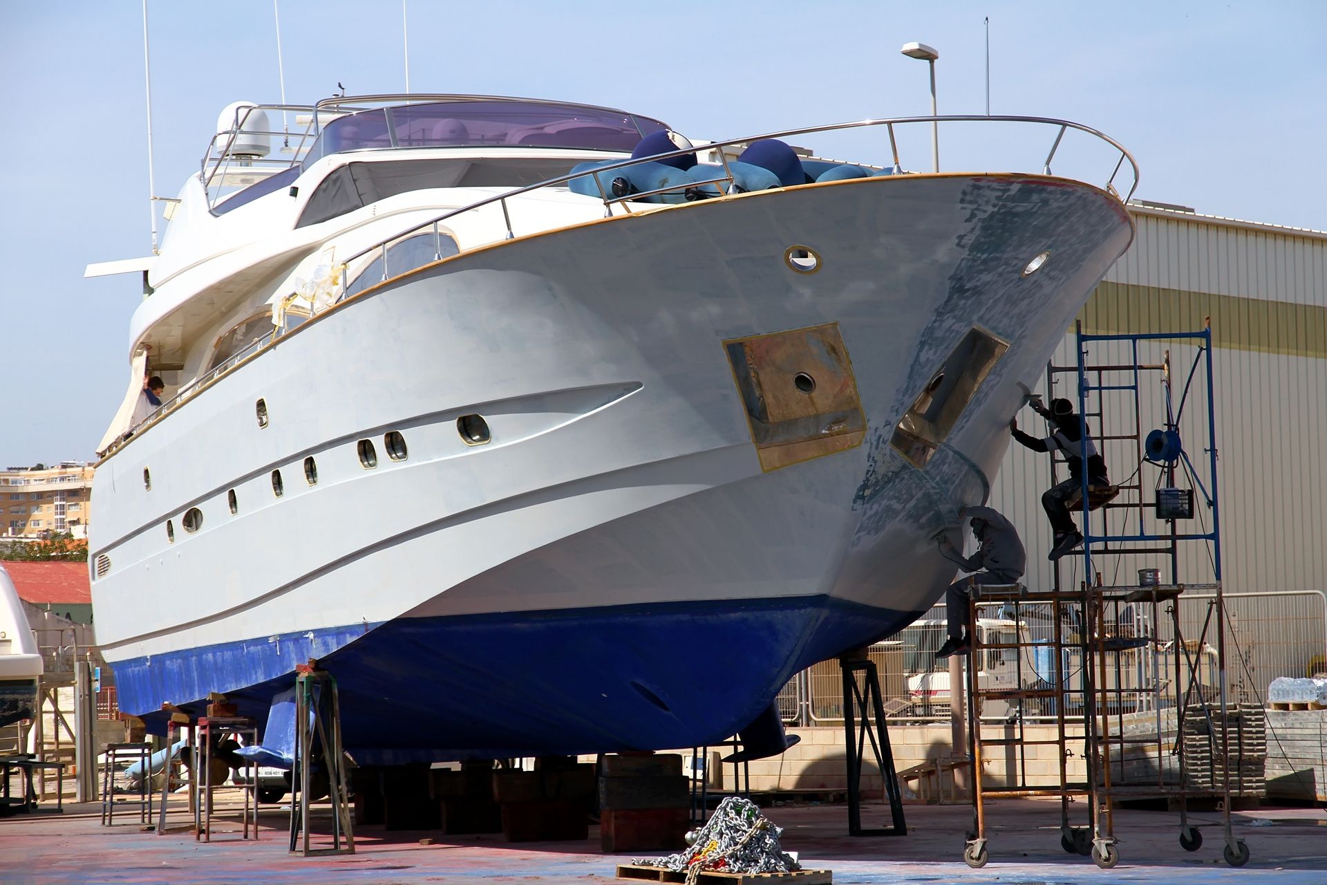 A large white yacht on supports being worked on by people on scaffolding