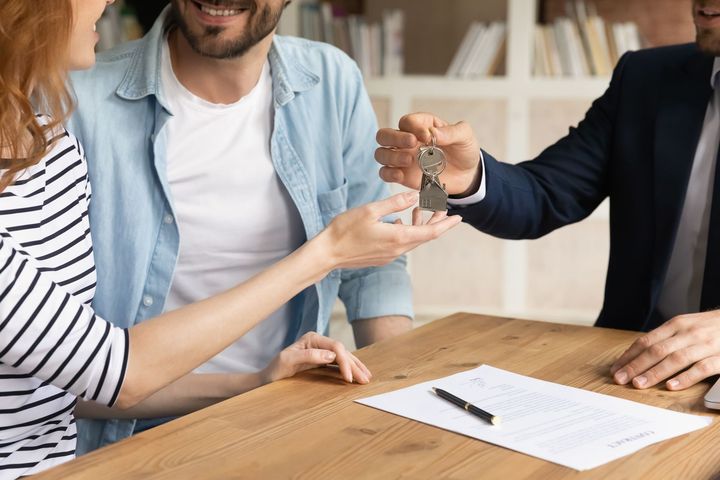 A man is giving a woman a set of keys