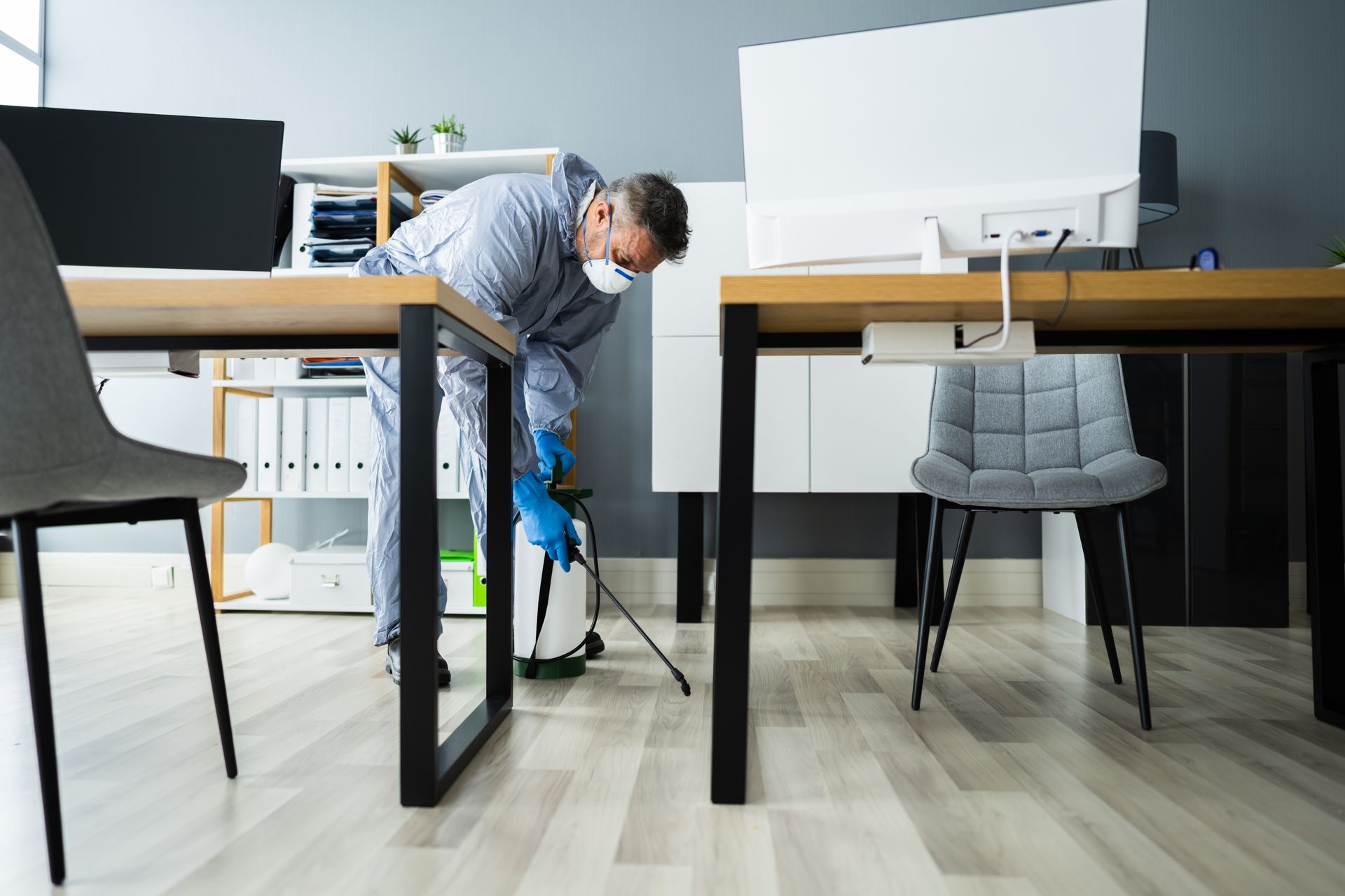 Pest control technician spraying insecticide in an office.