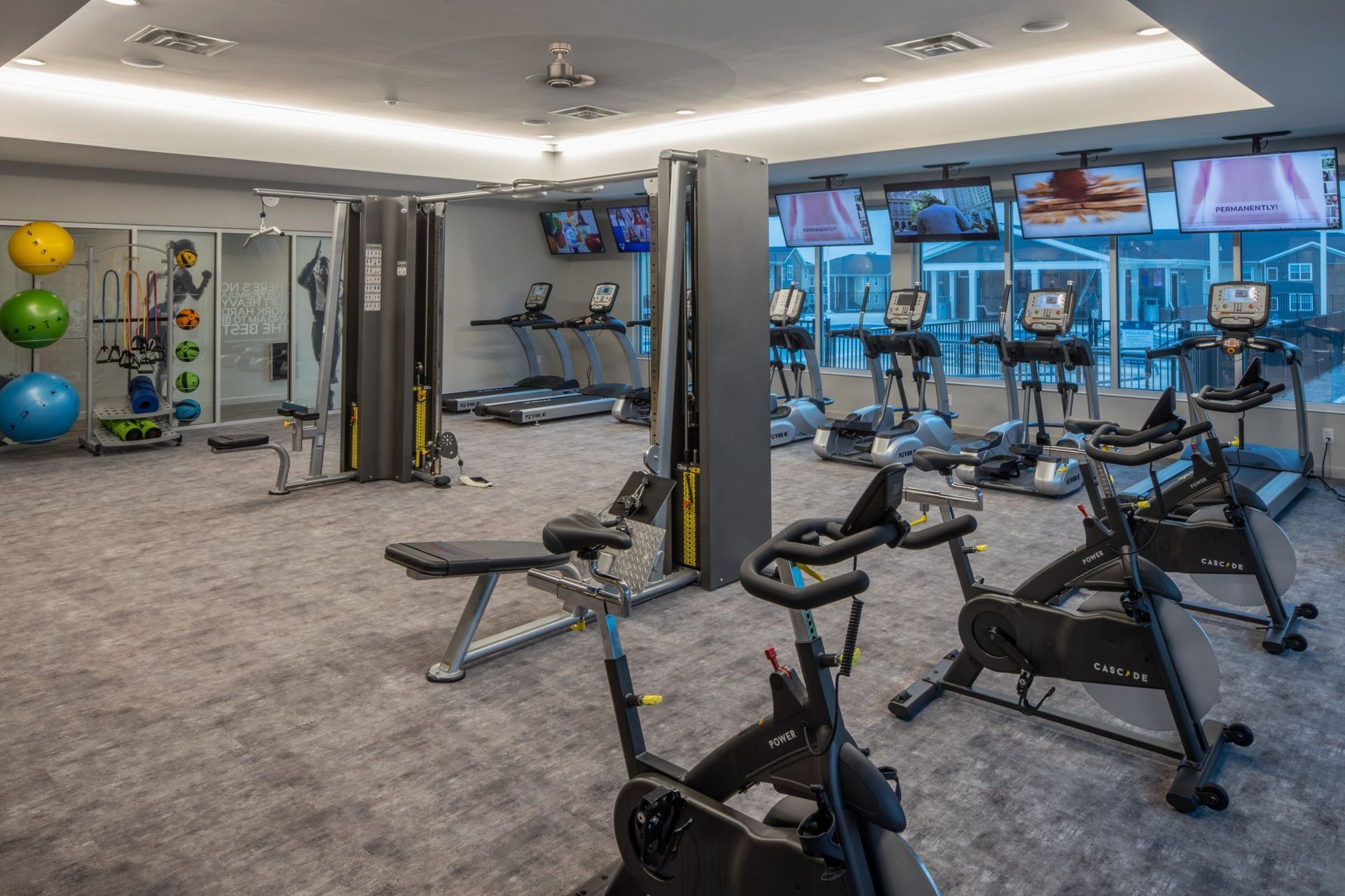 Modern fitness center with treadmills, bikes, and weight machines in a bright room.