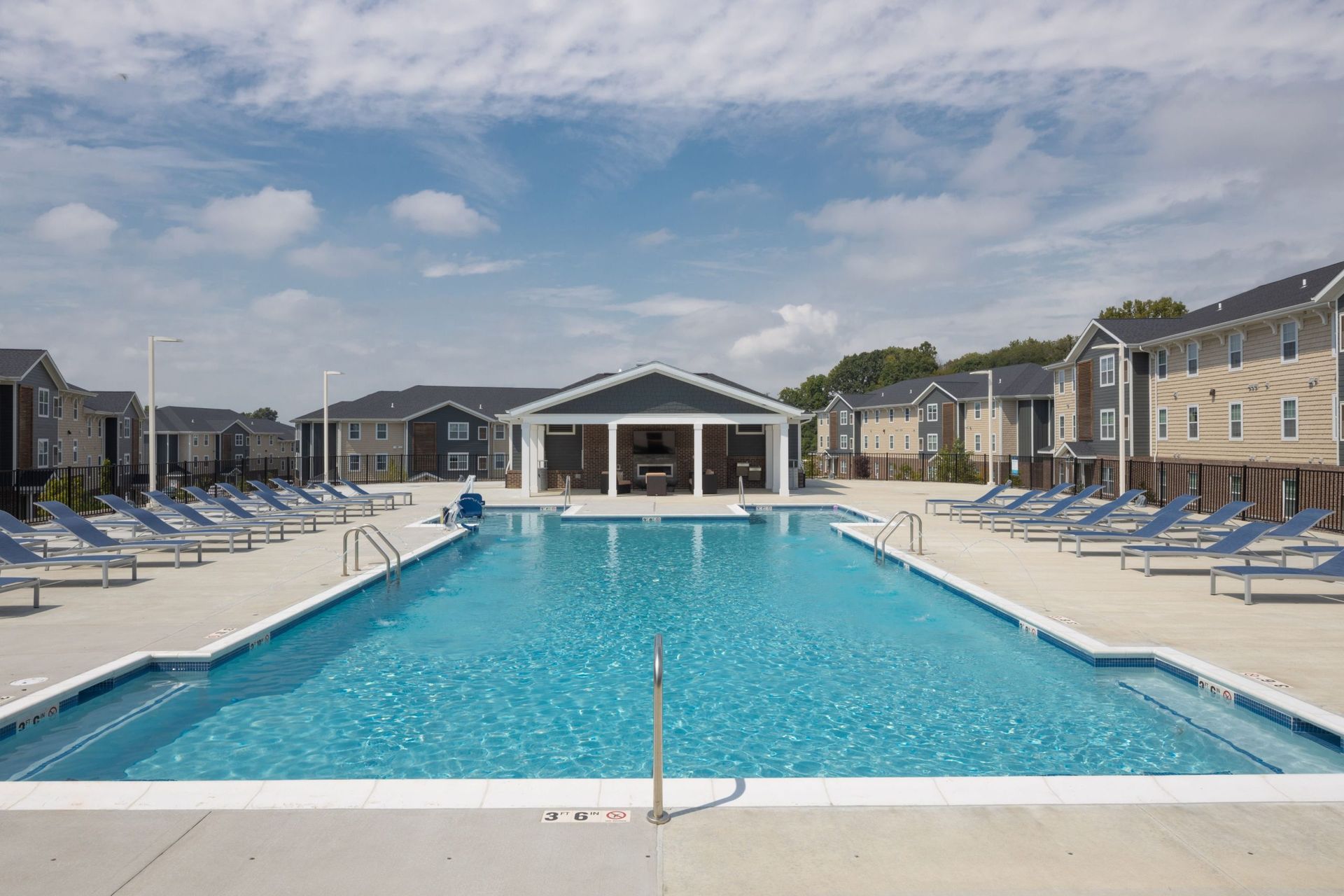 Outdoor community pool with blue water, lounge chairs, and a central pavilion.
