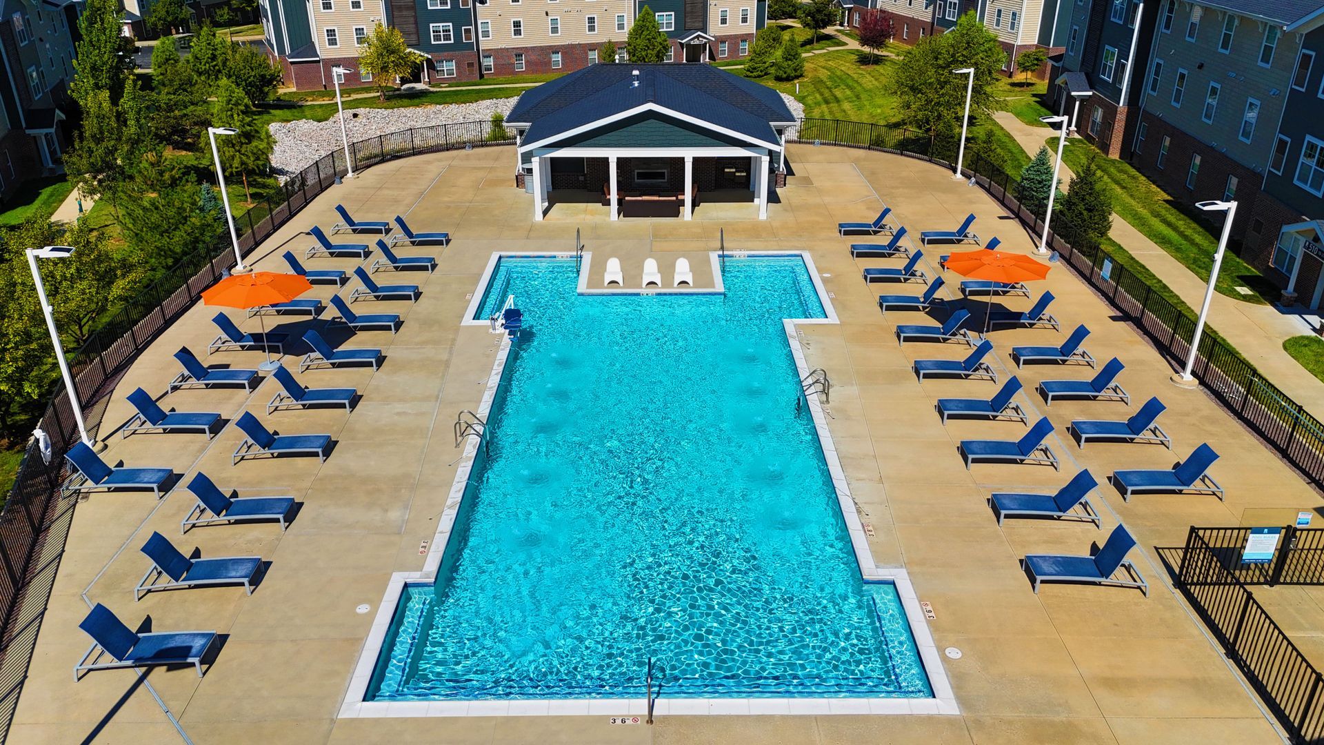Pool with lounge chairs and a pavilion at a residential complex.
