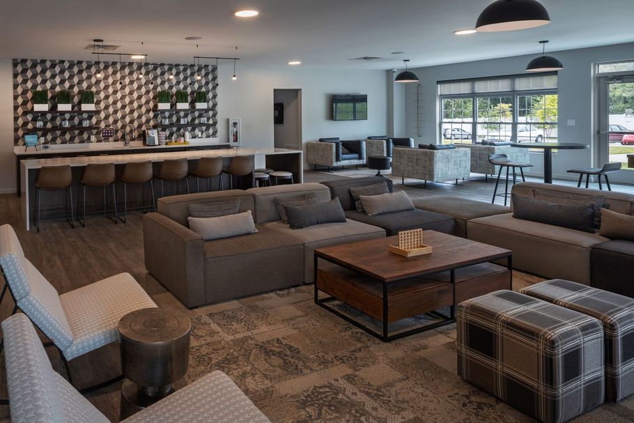 Modern lounge area with couches, bar, coffee table, and stools.
